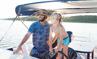 Ein Junge lernt mit seinem Vater das Hausbootfahren