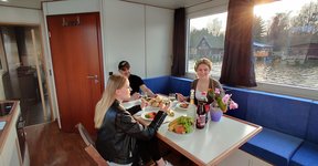 drei junge Menschen sitzen am Esstisch des Saunahausbootes und essen