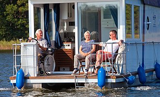 Der Skipper des barrierefreien Hausbootes sitzt im Rollstuhl.