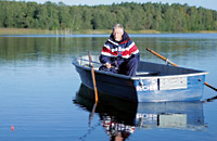 ein Ruderboot mit einem Herren auf einem ruhigen See
