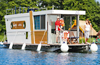 das Hausboot Febomobil 870 auf einem kleinen See mit einer Familie an Bord