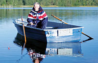 ein Ruderboot mit einer Person an Bord  liegt auf einem ruhigen See